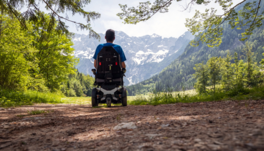 Personne en fauteuil roulant devant un paysage de randonnée Personne en fauteuil roulant devant un paysage de randonnée